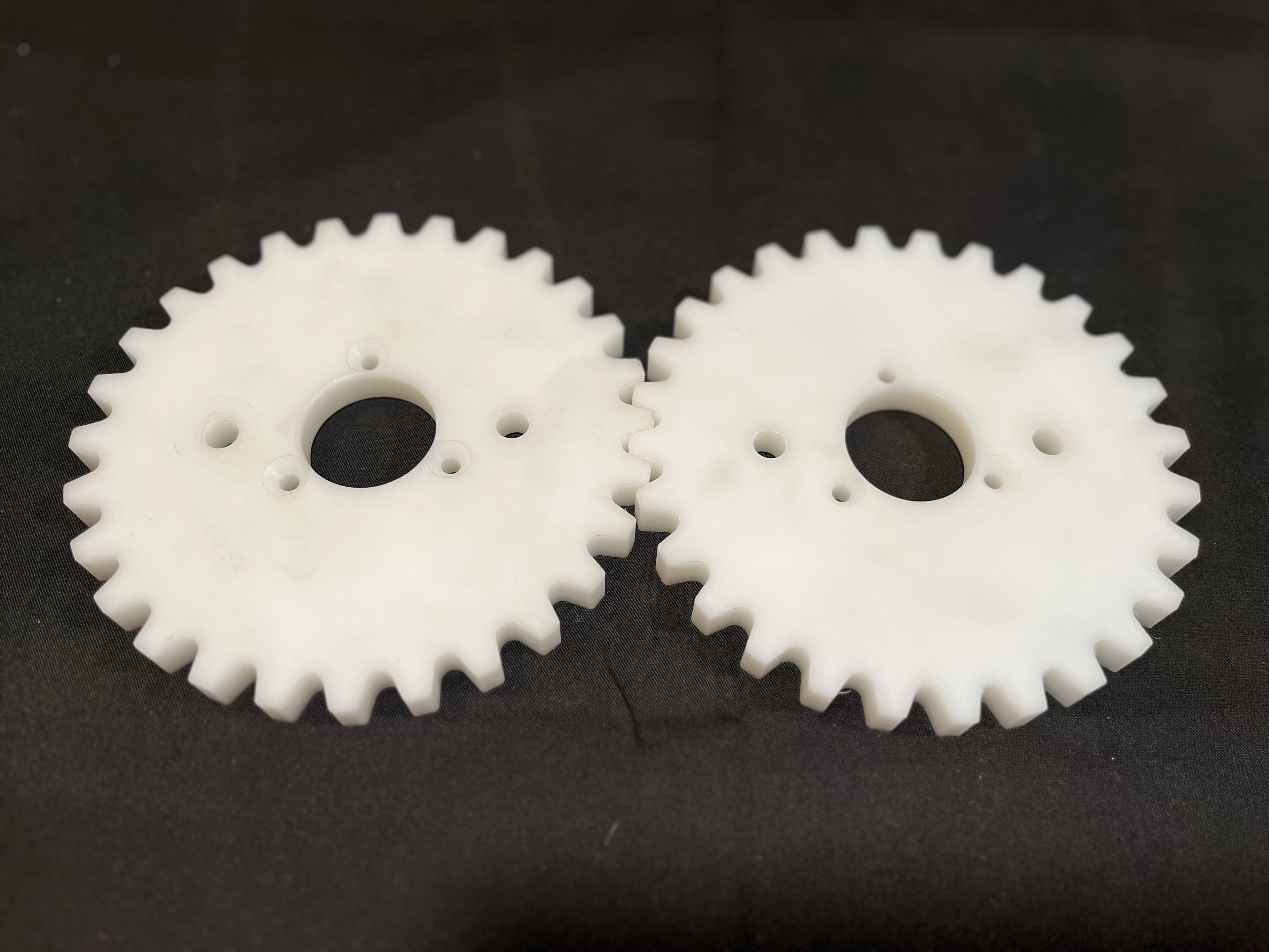 Two white plastic gears on a black background